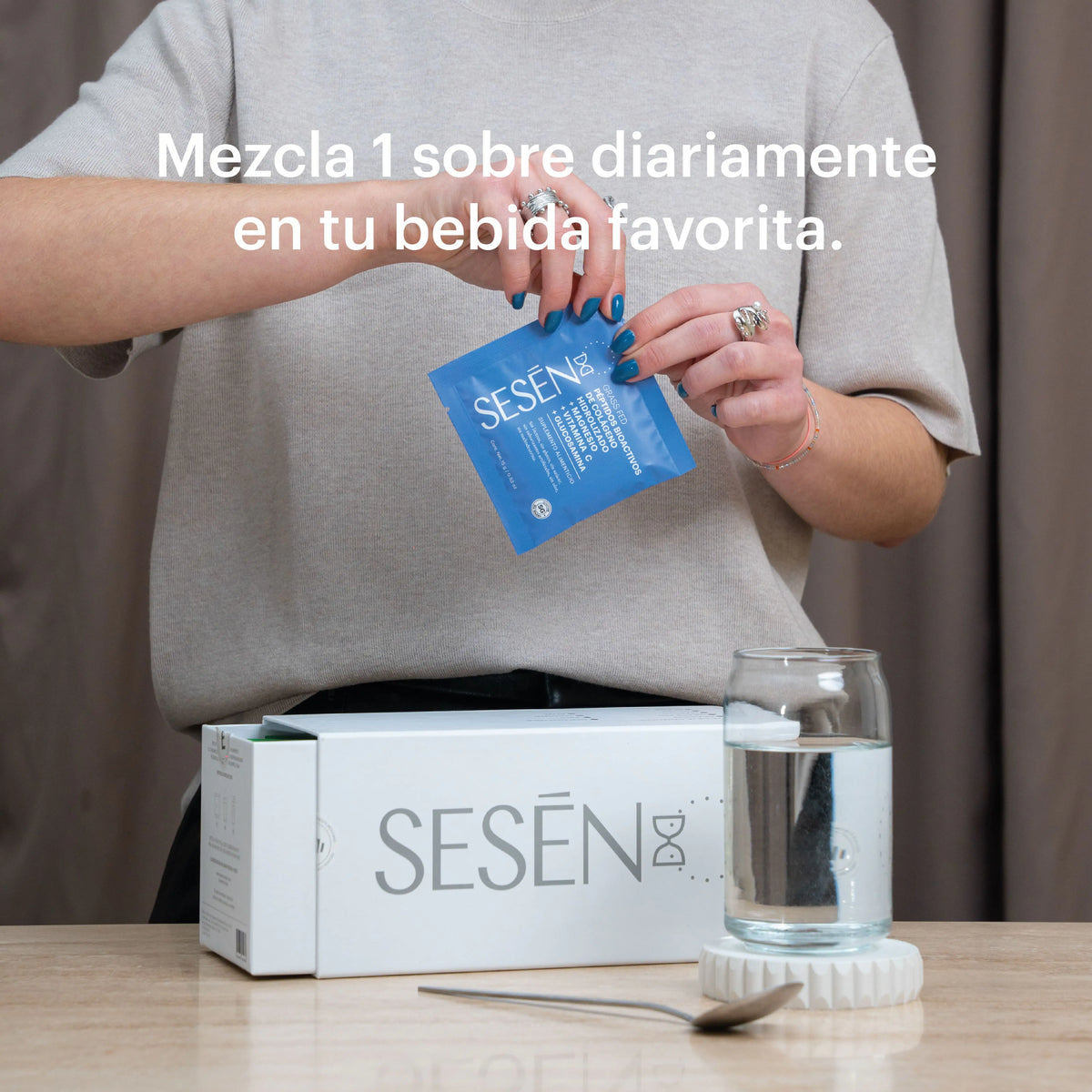 Persona sosteniendo un Sachet Blue y vertiendo el suplemento en una bebida con vaso de agua